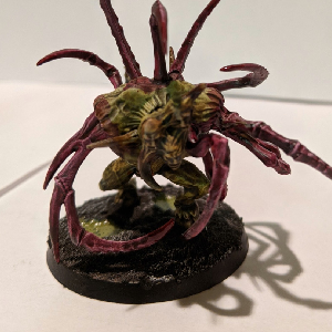 A photo of a green and pink chaos spawn with lots of pink crab claws.